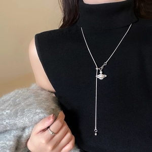 Collier perle en Y avec pendentif Saturne en zircon sur pull à col roulé noir