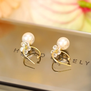 Detailed close-up of gold flower pearl earrings with sparkling zircon crystals