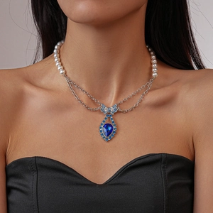 Detailed close-up of a vintage pearl necklace with a blue bow and teardrop gemstone