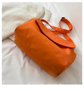 Detail view of the durable orange nylon fabric and adjustable strap of this crossbody bag
