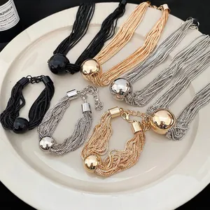 Multi-strand metal chain necklace with a large polished mirror ball bead in gold and silver