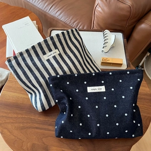 Close-up of striped and polka dot canvas cosmetic bags on a wooden table for storage