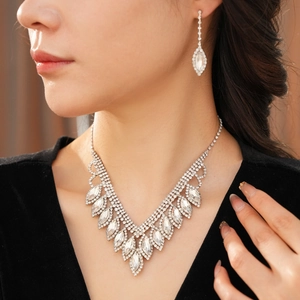 Close-up of elegant V-shaped diamond necklace and drop earrings set on female model