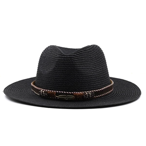 Détail d'un chapeau de paille noir avec ruban marron, plume en métal et broderie ethnique