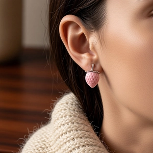 Detailed close-up of pink flocked strawberry stud earring with zircon accents on ear
