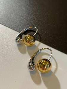 Macro detail of French vintage teardrop earrings with two-tone gold and silver metallic spheres