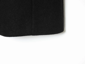 Macro shot of black wool blend fabric texture and stitching detail on the short coat