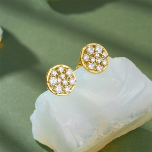 Macro shot of gold circular stud earrings with clear stones on white stone base