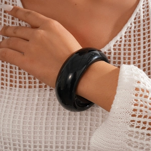 Macro shot of minimalist thick black resin bangle featuring a polished glossy finish