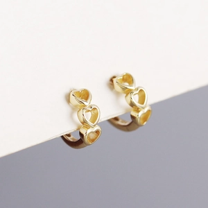 Macro shot of gold s925 silver triple hollow heart hoop earrings on display card