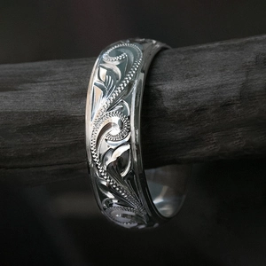 Classic silver engraved floral ring with vintage vine patterns on dark wood display