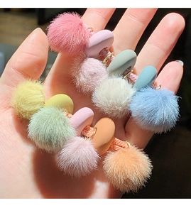 Dettaglio di pompon colorati e perline lisce su questi elastici per capelli morbidi