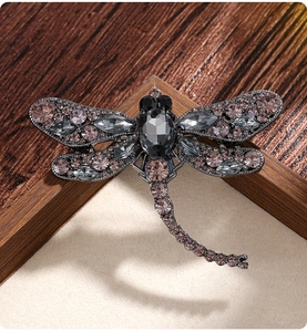 Macro shot of vintage dragonfly brooch with pink and grey crystals on dark metal