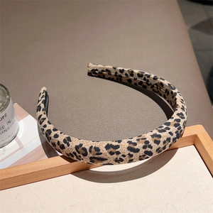 Macro shot of stylish leopard print headband with premium fabric texture on wooden tray