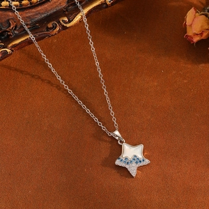 Detail shot of a star-shaped necklace with blue and white gems on a silver chain