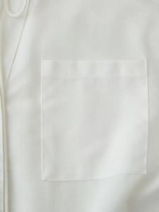 Detail view of white cotton linen fabric with woven drawstring and stitched pocket