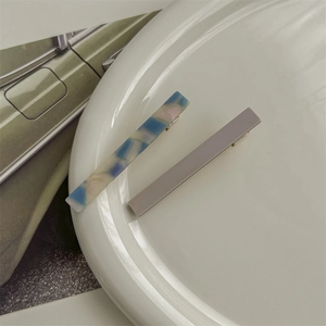 Detail of blue marble and grey acetate hair clips on a minimalist white plate