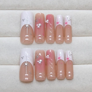Pink gradient press-on nails with French starburst design and 3D pearls on a tray