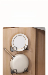 Close-up of gunmetal kitchen rack holding a white ceramic plate and a wooden handle pan