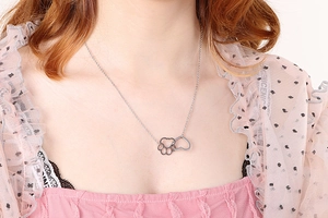 Polished titanium steel necklace featuring a hollow cat paw and heart charm on a model