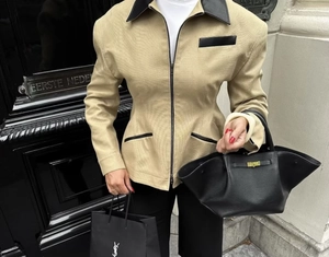 Close-up of khaki jacket with black leather patchwork details and a slim waist design