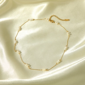 Detailed shot of a gold beaded necklace on silk with lobster clasp and extension chain
