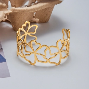 Detail of gold hollow floral cut-outs on the stainless steel adjustable cuff bracelet