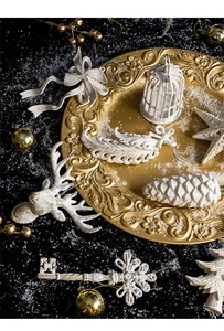 Detail view of vintage white and gold Christmas ornaments on an elegant golden tray