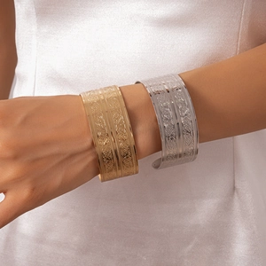 Close-up of gold and silver vintage cuff bracelets with intricate floral carvings