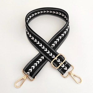 Detail of black nylon strap with white arrow pattern and golden metal buckles