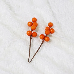 Close-up of artificial orange berries on white faux fur background for DIY home decor