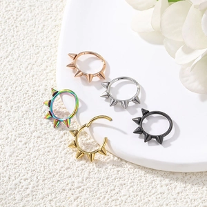 Detailed display of five colorful spiked steel nose rings on a white display tray