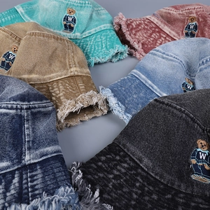 Detail of washed denim bucket hats with frayed edges and embroidered bear patches