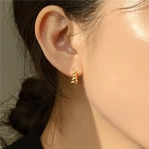 Close-up of gold layered bead hoop earrings with wave texture worn on model's ear
