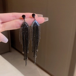 Detailed close-up of elegant black tassel earrings with rhinestones held by hand