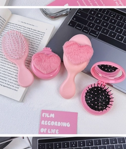 Close-up of pink plush heart hairbrushes and folding mirror comb on a desk setup