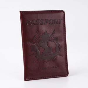 Detail of burgundy PU leather passport cover with embossed gold logo and travel icons