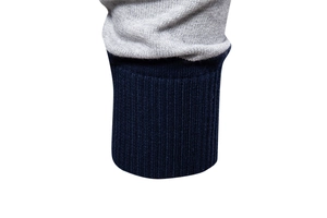 Detail von grauem Strickstoff mit dunkelblauen Rippbündchen an einem Herren-Langarm-Poloshirt