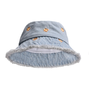 Close-up of light blue denim bucket hat featuring orange flower embroidery and frayed edges
