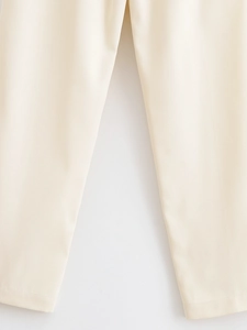 Close-up detail of cream high-waisted trousers showing fabric texture and crotch stitching