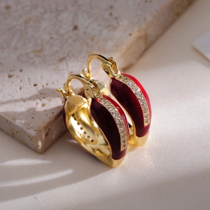 Macro detail of French vintage gold earrings with deep red enamel and white zircons