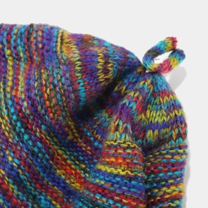 Macro shot of colorful knitted hat details featuring chunky bohemian braided yarn texture