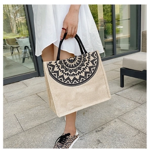 Outdoor shot of a linen tote bag featuring black geometric ethnic patterns on natural jute