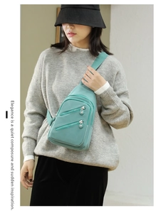 Detail view of mint green nylon crossbody bag with dual metallic zippers and adjustable strap