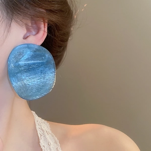 Close-up of a blue resin teardrop earring with ice-cracked texture on model's ear