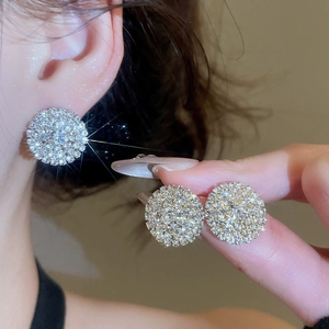 Close-up of golden round paved crystal stud earrings showing luxury sparkle and detail