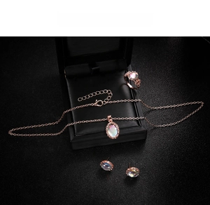 Macro view of rose gold jewelry set featuring iridescent opal stones in a black gift box
