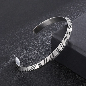 Detailed view of silver titanium steel cuff featuring geometric herringbone patterns