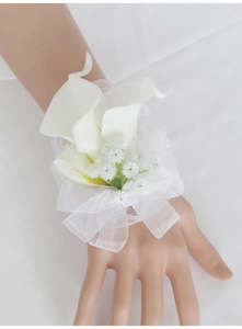 Detail of white calla lily wrist corsage with baby's breath and organza bow for weddings