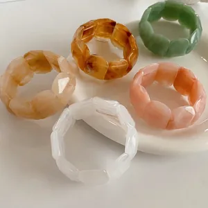 Chic multi-faceted acrylic resin cuff bracelets with vintage marble patterns on a ceramic tray